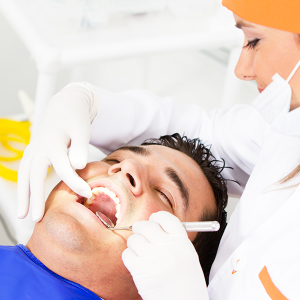A man's teeth are examined at a dentist's office.