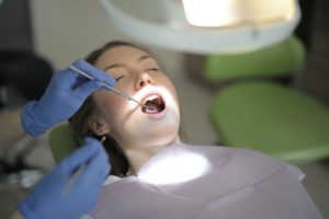 How long does dental numbing last? It's a question many patients of our Grosse Pointe dental office ask, but the time varies depending on several factors. In this image, a dental professional uses a mirror to look at the inside of a patient's lower teeth.