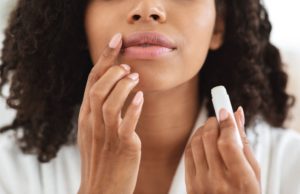 Help prevent lip cancer by using lip balm with SPF protection. In this image, a woman applies sunscreen to her lips.