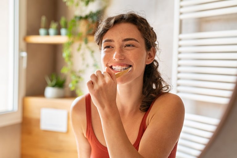 Prevent acid erosion of teeth during the holidays by brushing and flossing properly, as represented by this picture of a woman brushing her teeth.