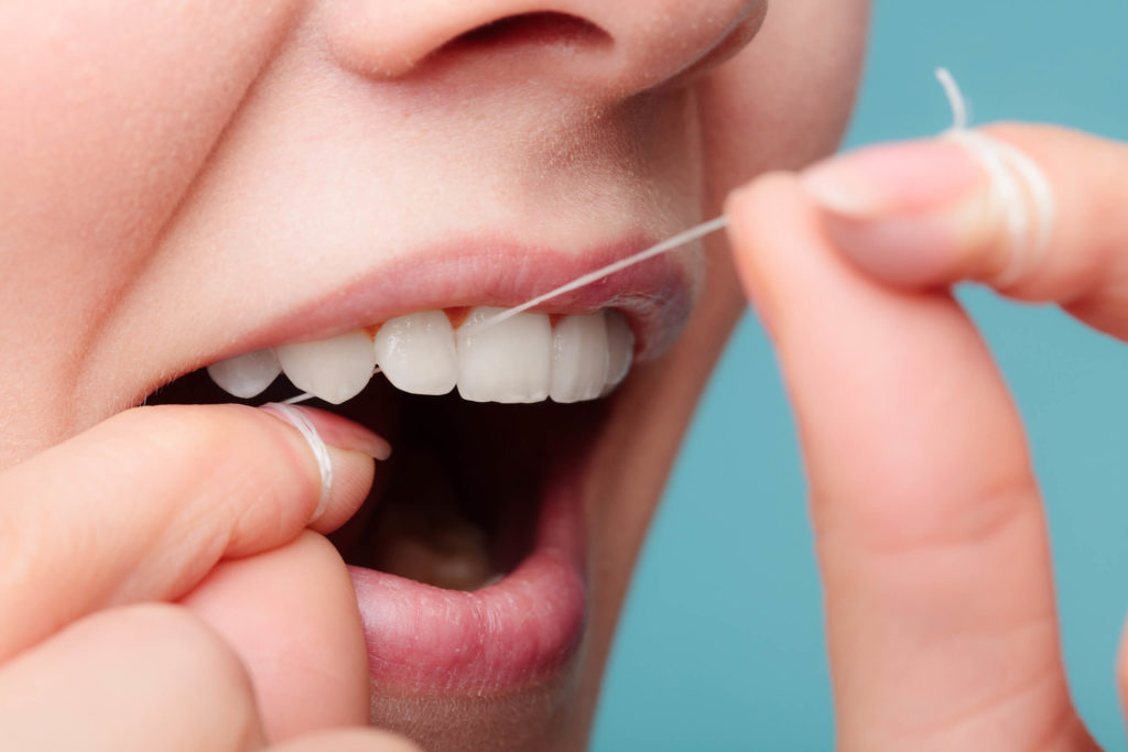 person flossing between teeth up close